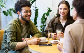 happy young man at a table with two friends having coffee